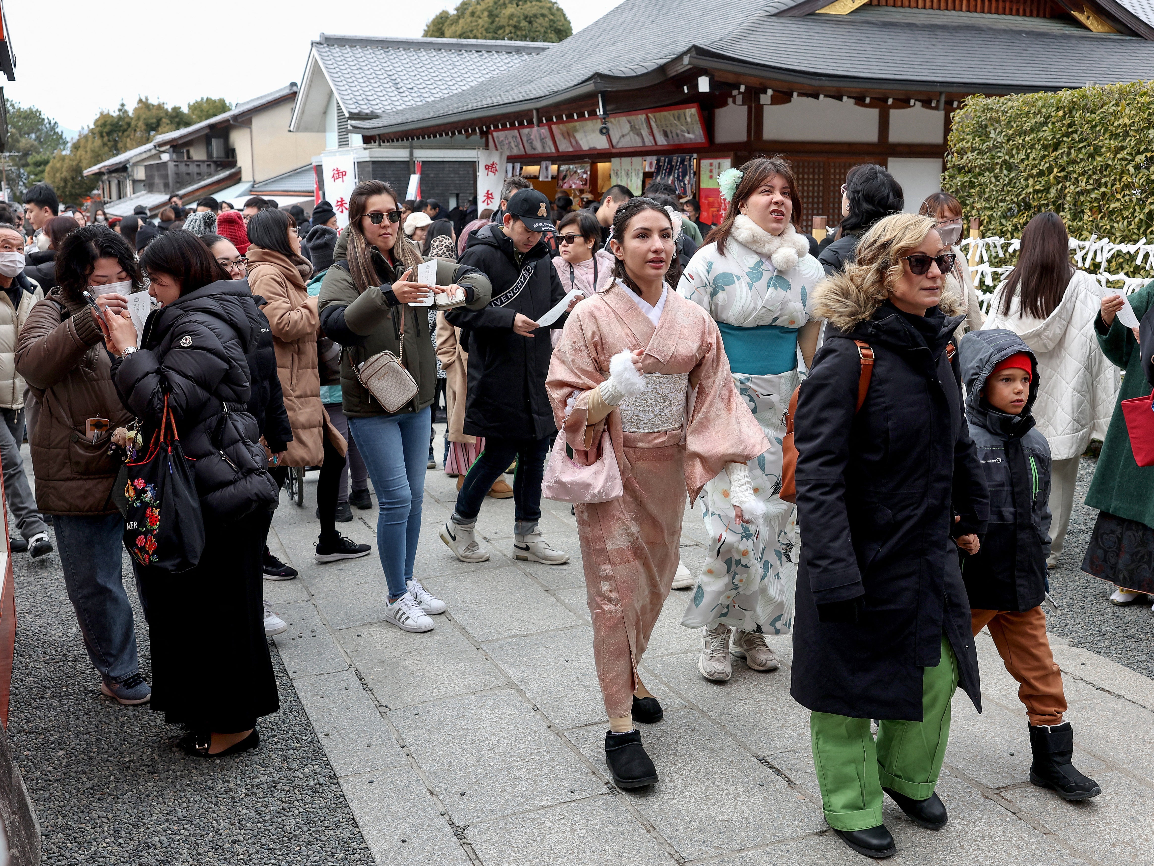 Tourists walk past shops during a visit to Fushimi Inari Shrine in the city of Kyoto on 13 January 2025